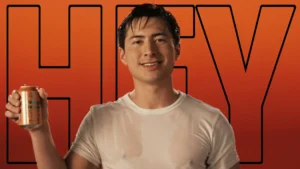 Shane Hollander holding a soft drink and wearing a wet t-shirt. The word HEY is outlined behind him on a orange background. This is the cover image of the iconic Big Ole Freak Heated Rivalry edit by (im)sosaneitsinsane.
