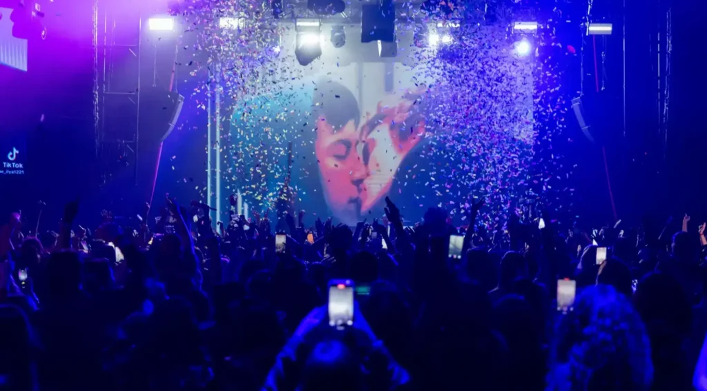 Confetti falls on a dance floor as a scene from “Heated Rivalry” of Shane Hollander (Hudson Williams) and Ilya Rozanov (Connor Storrie) plays at a themed night at the Vermont Hollywood on Jan. 9. (Ronaldo Bolanos / Los Angeles Times)